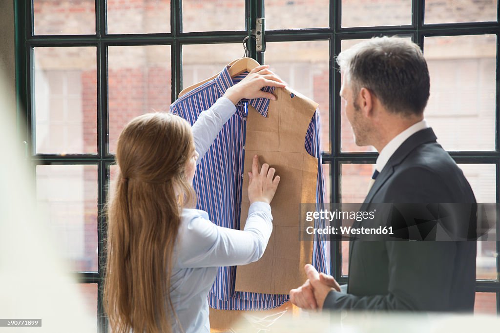 Young seamstress showing customer tailor made shirt