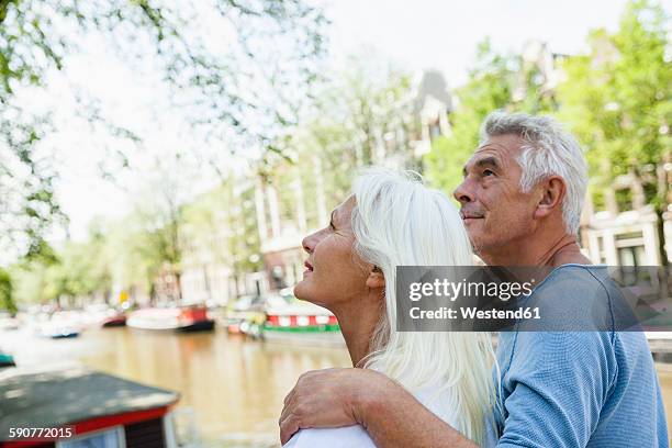 netherlands, amsterdam, senior couple at town canal looking up - amsterdam canal stockfoto's en -beelden