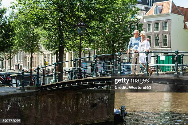 netherlands, amsterdam, senior couple walking on a bridge - grachtenpand stock pictures, royalty-free photos & images