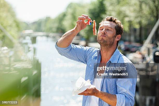 netherlands, amsterdam, man eating matjes herring - dutch flag stock pictures, royalty-free photos & images