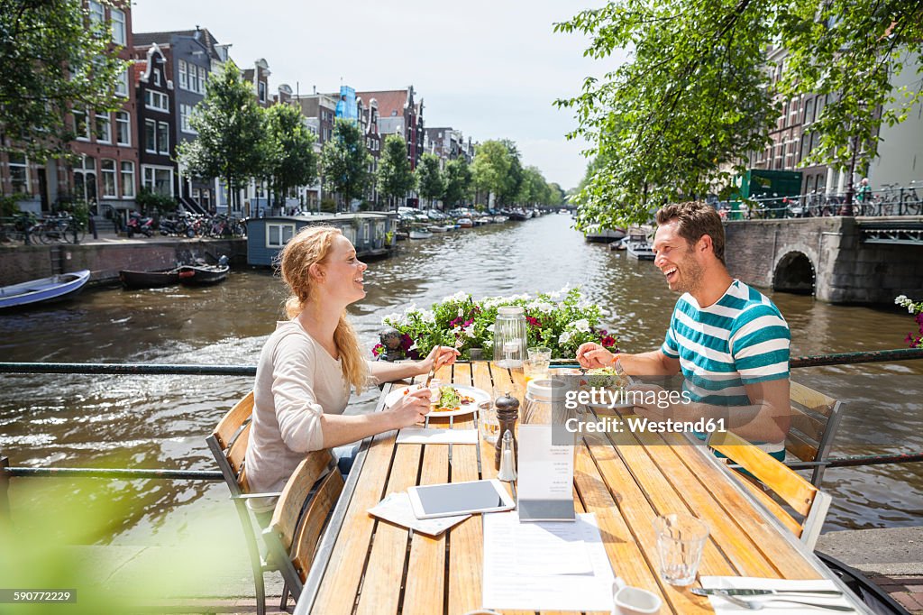Netherlands, Amsterdam, happy couple having lunch at town canal