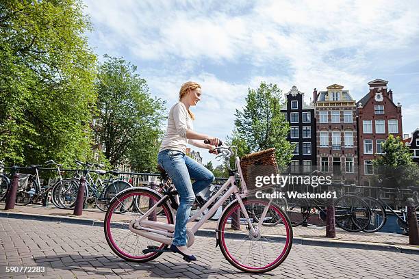 netherlands, amsterdam, woman riding bicycle in the city - amsterdam cycling stock pictures, royalty-free photos & images