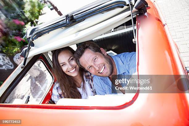 happy couple looking through open sunroof of a small car - sunroof stock pictures, royalty-free photos & images