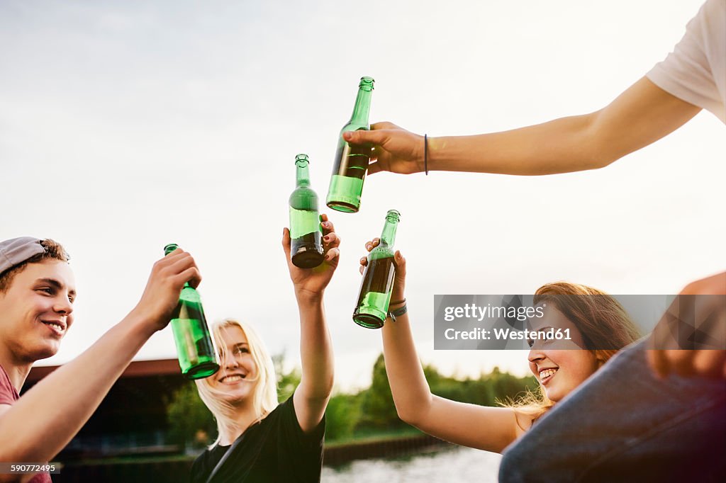 Friends drinking beer together at the waterside