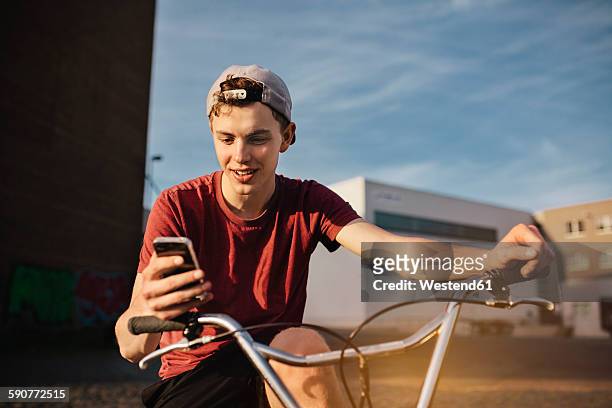 young man with bmx bicycle looking on cell phone - 漢諾威 個照片及圖片檔