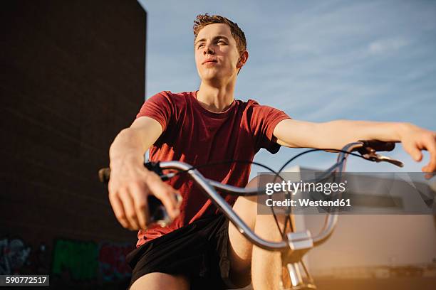 young man with bmx bicycle looking away - bmx stock-fotos und bilder