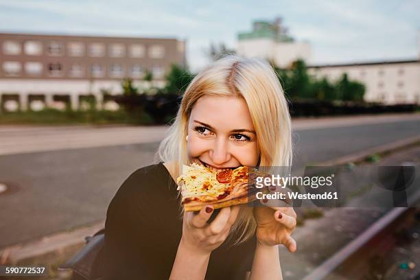 friends sitting together outdoors sharing a pizza - pizza stock pictures, royalty-free photos & images