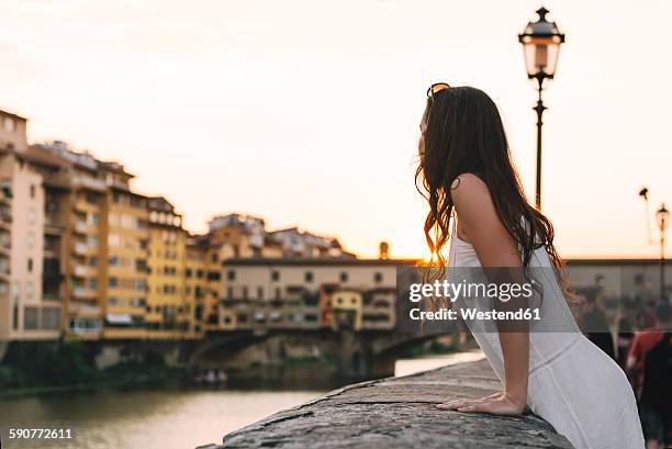 italy, florence, woman watching sunset behind ponte vecchio - balustrade foto e immagini stock