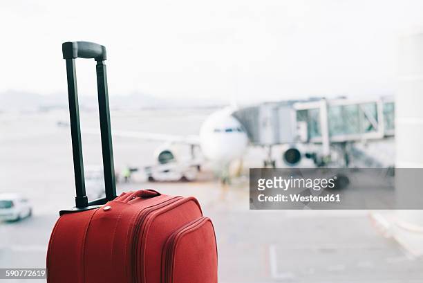 red suitcase at airport, airplane in background - valises bagages stock-fotos und bilder