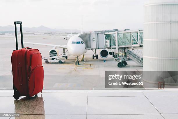 red suitcase at airport, airplane in background - luggage trolley stock-fotos und bilder