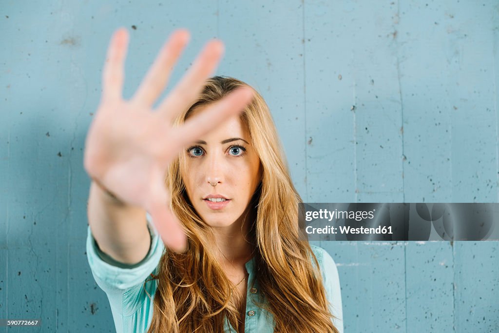 Young blond woman raising her hand