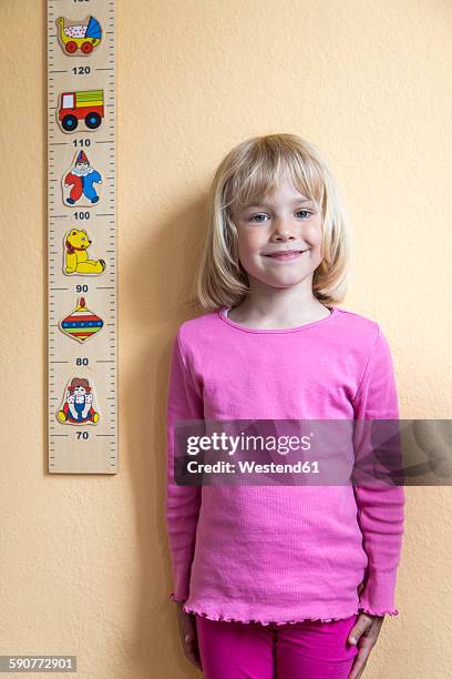 portrait of smiling little girl standing beside a yardstick - duimstok stockfoto's en -beelden