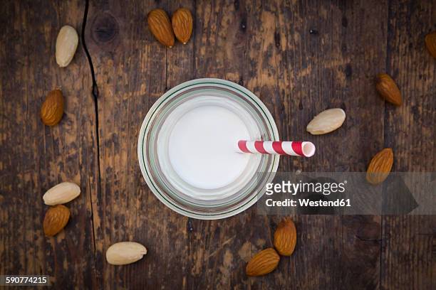 almond milk in glass, drinking straw, on wood - straw ストックフォトと画像