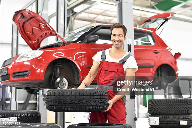 car mechanic in a workshop, changing tire - winter tyre stock pictures, royalty-free photos & images