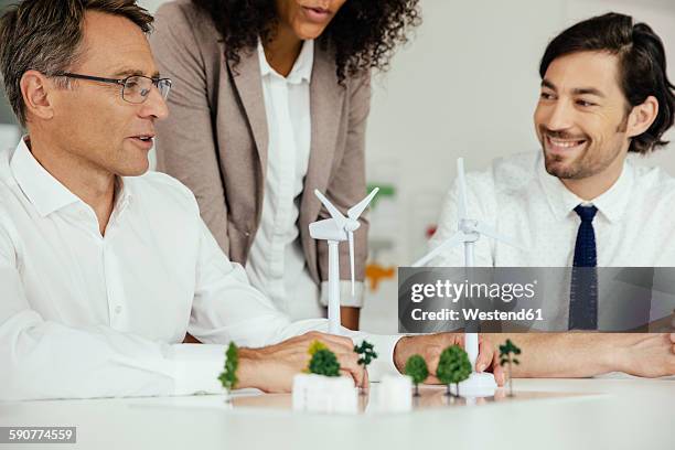 business people discussing wind turbine model and houses on conference table - 16 year old models stock pictures, royalty-free photos & images