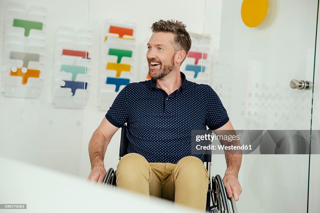 Smiling man in wheelchair in modern office