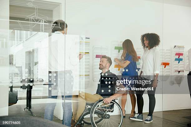 colleagues talking in office with one sitting in wheelchair - girl business photos et images de collection