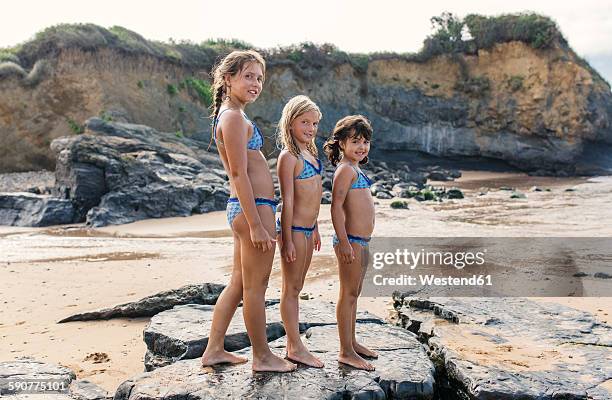 spain, colunga, three girls standing in a row on the beach - preteen swimwear bildbanksfoton och bilder