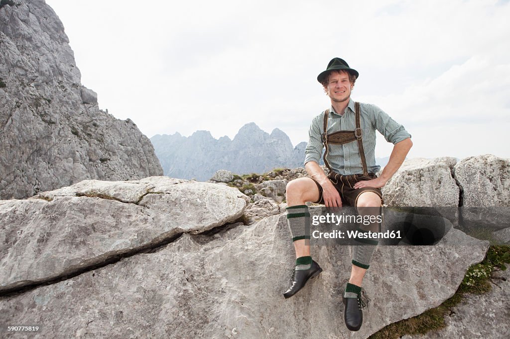 Germany, Bavaria, Osterfelderkopf, man in traditional clothes sitting in mountain landscape