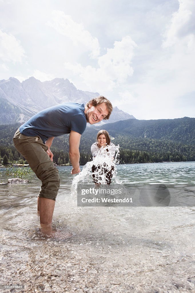 Germany, Bavaria, Eibsee, playful couple splashing in water