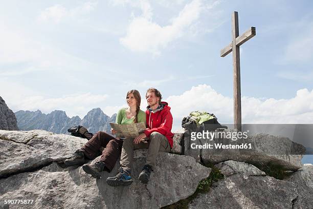 germany, bavaria, osterfelderkopf, couple with map resting at summit cross - gipfelkreuz stock-fotos und bilder