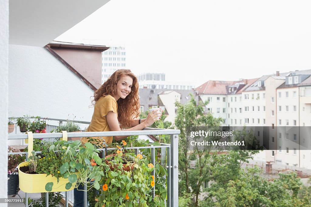 Smiling woman with cup of coffee on balcony
