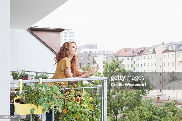 smiling woman with cup of coffee on balcony - frau balkon stock-fotos und bilder