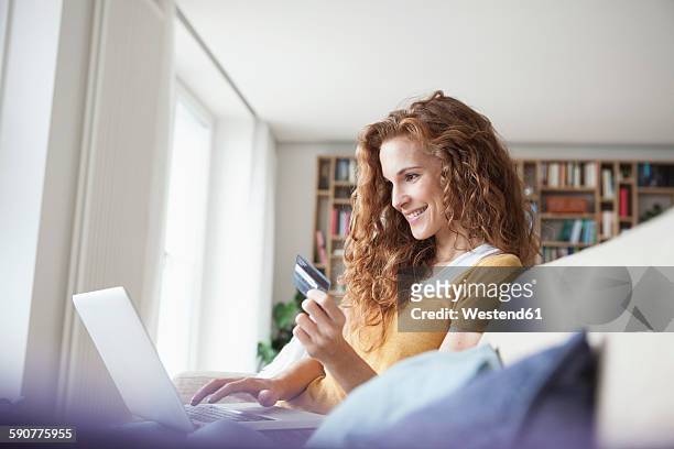 smiling woman at home shopping online - shopping credit card stock-fotos und bilder