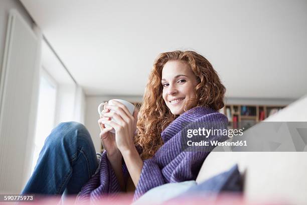 smiling woman at home sitting on couch holding cup - lounge munich photos et images de collection