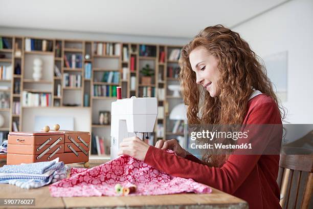 smiling woman at home using sewing machine - nähen stock-fotos und bilder