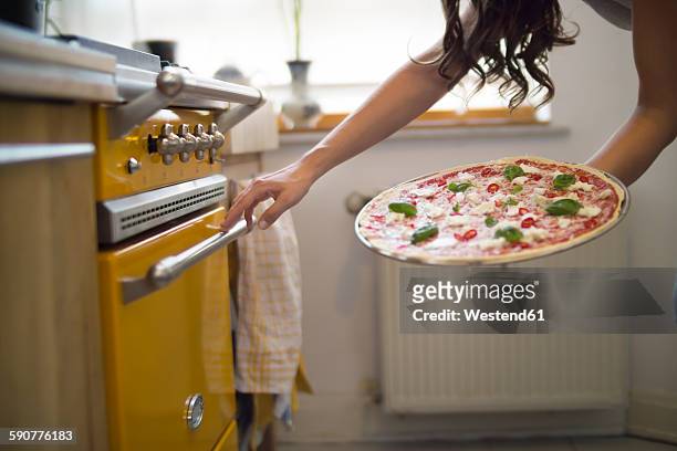 young woman holding homemade pizza with mozzarella, chili peppers and basil - backofen stock-fotos und bilder