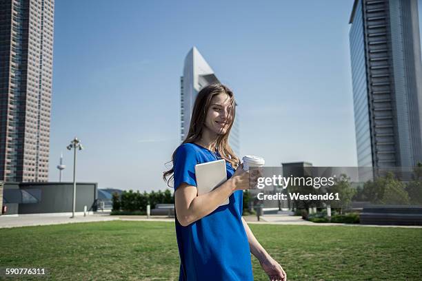 germany, frankfurt, smiling woman with coffee to go and mini tablet - business woman blue stock-fotos und bilder