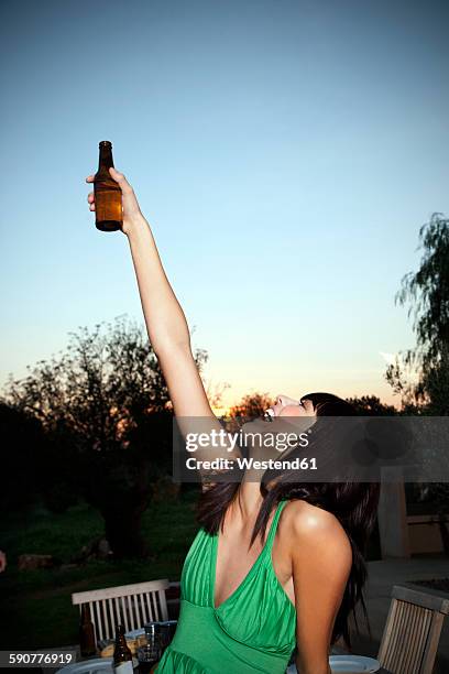 happy young woman lifting a beer at sunset - holding beer stock pictures, royalty-free photos & images