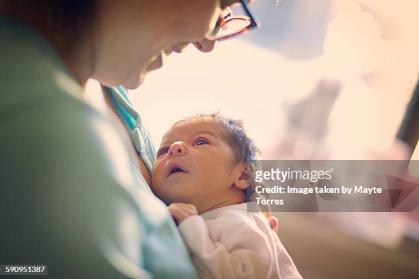 mom smiling at newborn at hospital - neu stock-fotos und bilder