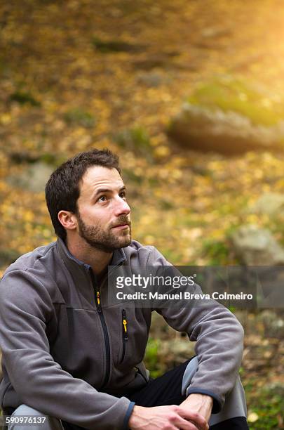 carefree man seated in the woods - velo casaco imagens e fotografias de stock