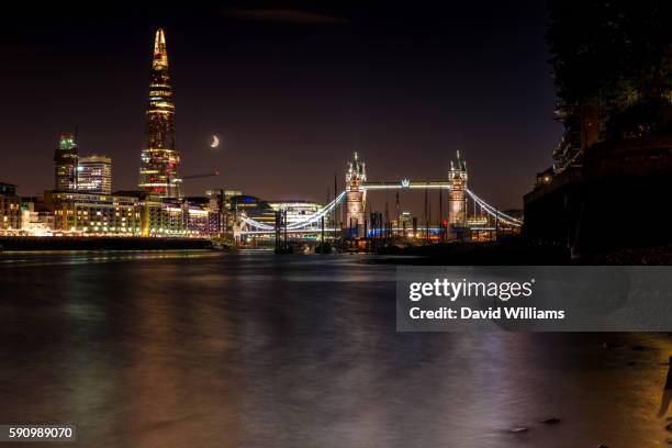 shad thames, the shard, tower bridge, butler's wharf viewed at night from the banks of the river thames as the moon sets behind them - shad stock pictures, royalty-free photos & images