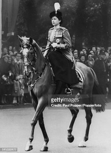 Princess Elizabeth, pictured wearing a scarlet and gold tunic, bearskin tricorne hat with osprey plume and Order of the Garter emblem, as she rides...