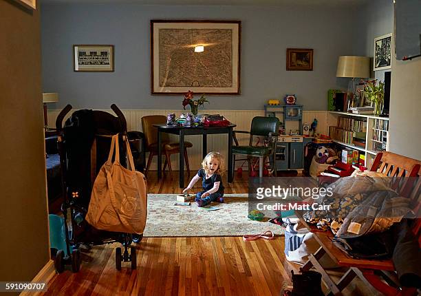 toddler playing in messy room - girl sitting on floor stock-fotos und bilder