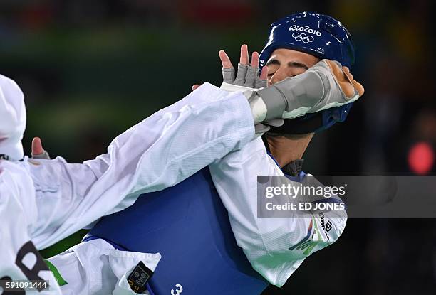 Israel's Ron Atias is kicked by Brazil's Venilton Teixeira during their men's taekwondo qualifying bout in the -58kg category as part of the Rio 2016...