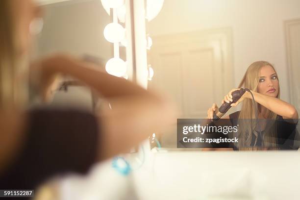 young woman using curling iron - lockenstab stock-fotos und bilder