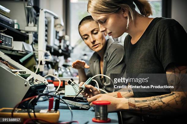 female technician guiding young trainee - unterrichten stock-fotos und bilder