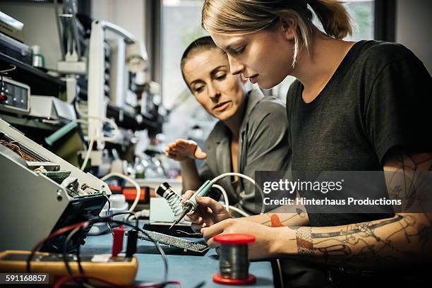 female technician guiding young trainee - aprendiz fotografías e imágenes de stock