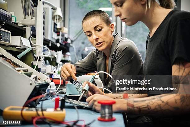 female technician guiding young trainee - leitwarte stock-fotos und bilder