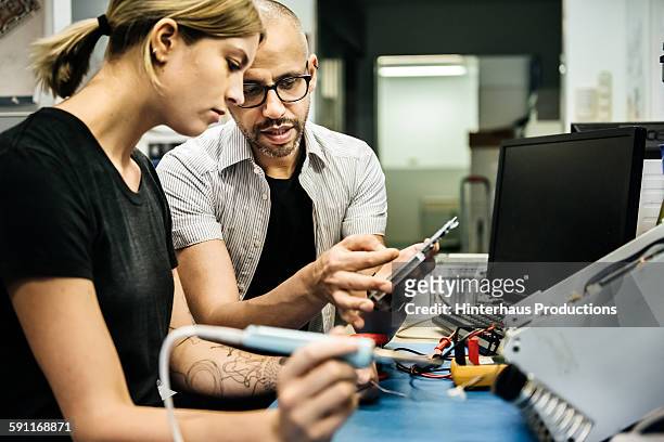 technician guiding female trainee in workshop - apprenti photos et images de collection