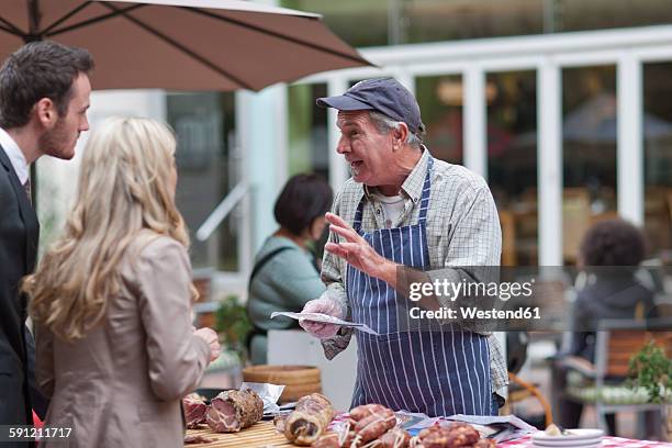 man selling sausage at city market - market stall stock pictures, royalty-free photos & images