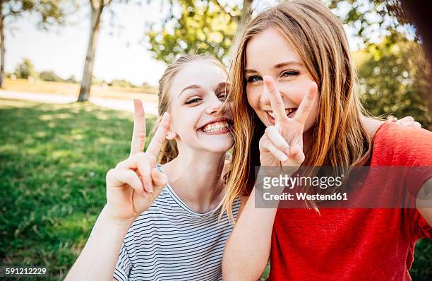 two playful teenage girls making victory sign - girl selfie fotografías e imágenes de stock