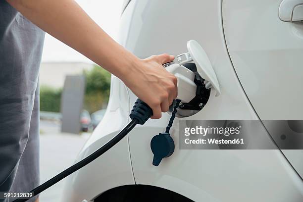 young woman charging electric car - recharging stock pictures, royalty-free photos & images
