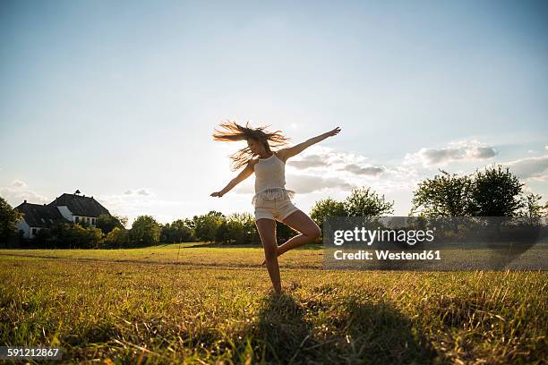 Young woman dancing on a meadow at backlight