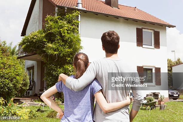 couple in garden looking at residential house - see stockfoto's en -beelden