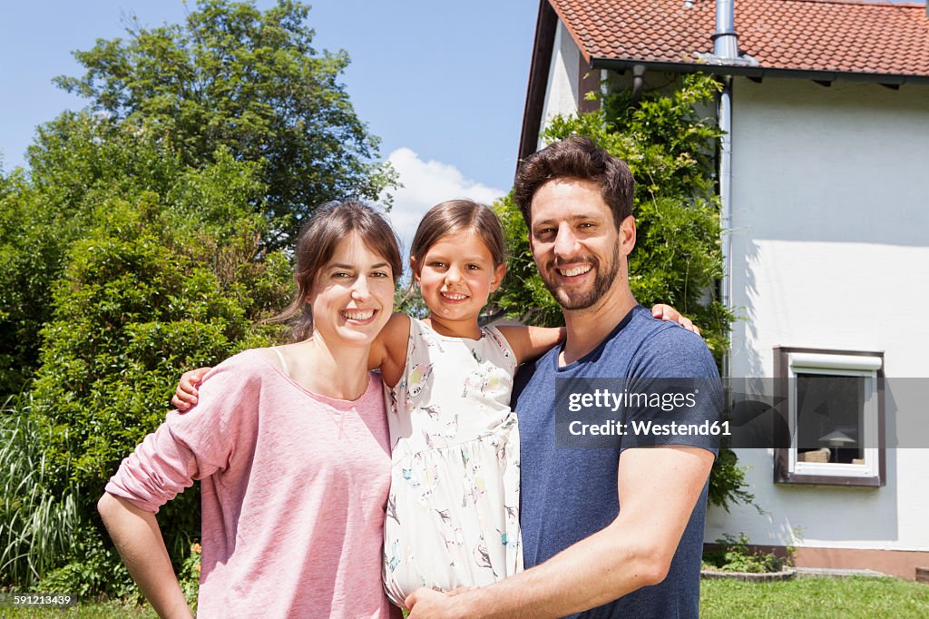 Portrait of smiling family with daughter in garden